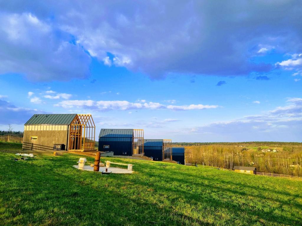 a green field with two buildings in a field at Domki Mocy Orzechówka in Bodzentyn
