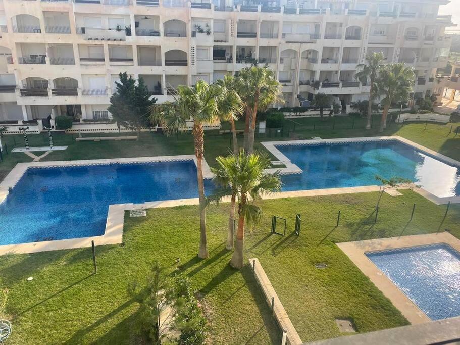 a large pool with palm trees in front of a building at Vereda Golf - Apartamento in Roquetas de Mar