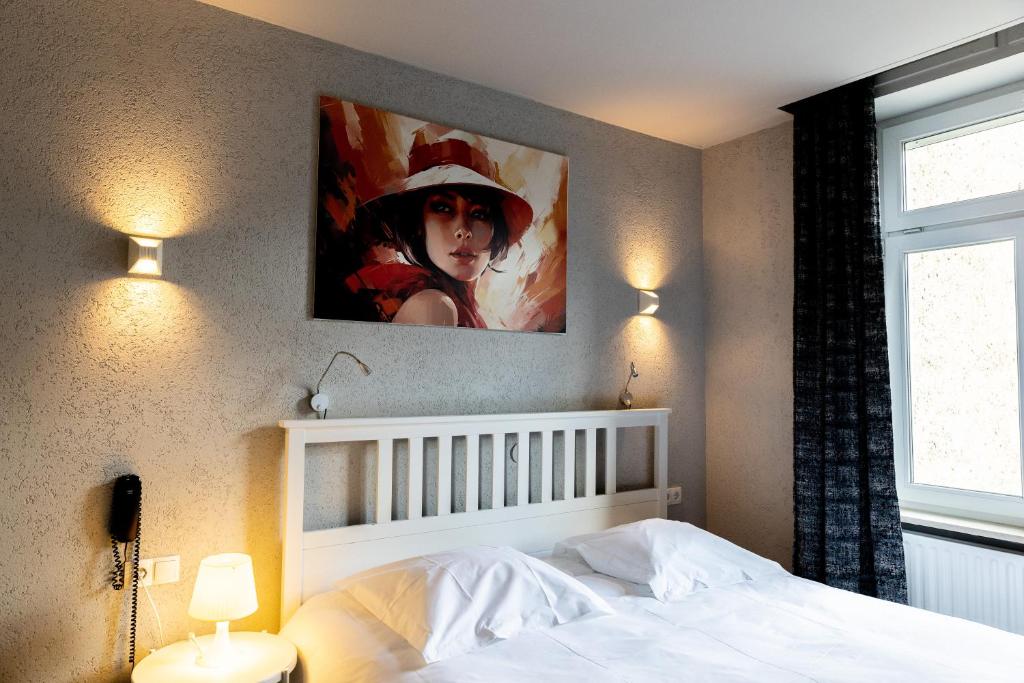 a bedroom with a white bed with a painting on the wall at Hotel Bristol in Luxembourg