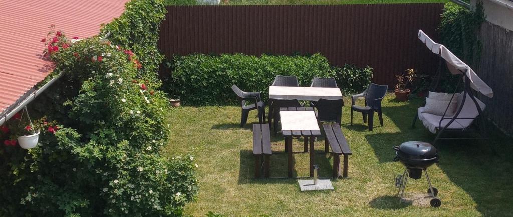 einen Garten mit einem Tisch, Stühlen und einem Grill in der Unterkunft Emma vendégház in Sárospatak