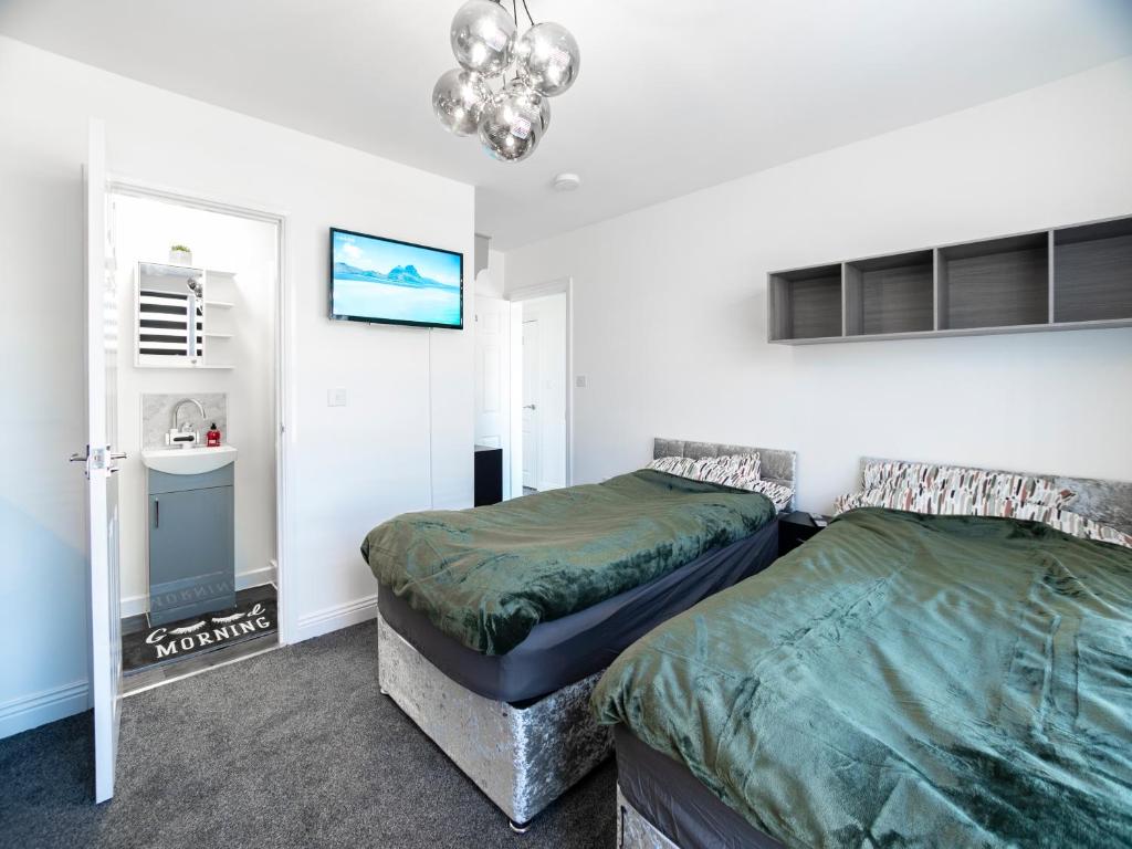 a bedroom with two beds and a chandelier at Mansfield Town Centre Flats in Mansfield