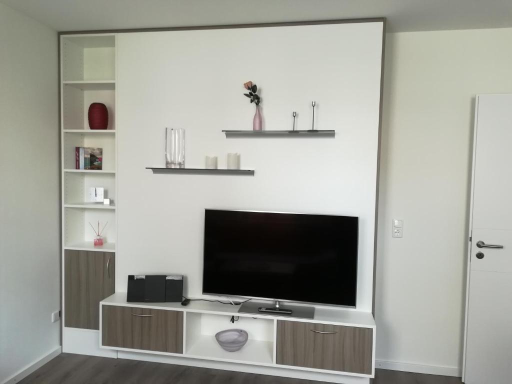 a living room with a television on a white wall at Apart Schleswig in Schleswig