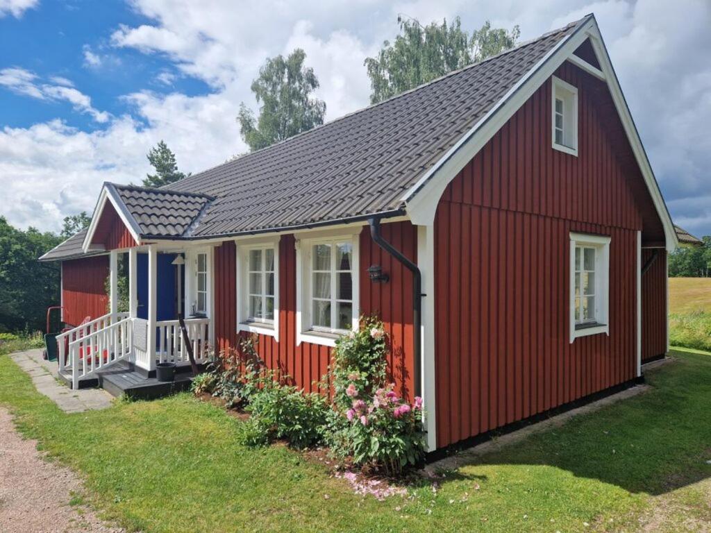 a red shed with white windows and a porch at The Wine Lodge-Bo på vingård in Vittsjö