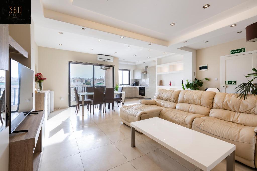 een woonkamer met een bank en een tafel bij Beautiful, spacious 3BR home with private Balcony with 360 Estates in St Julian's