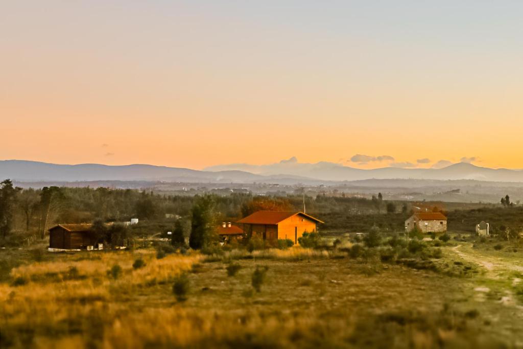 a house in a field with the sunset in the background at Vila da Laje - Onde a Natureza o envolve - Serra da Estrela in Oliveira do Hospital