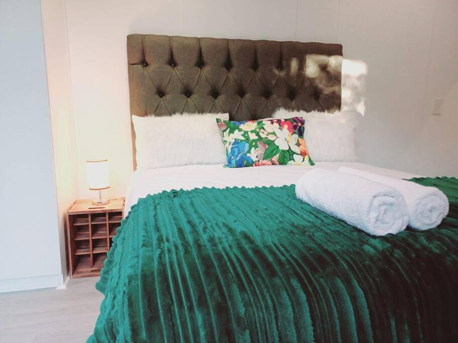 1 cama con edredón verde y almohadas en Charm Nest - Uncapped Wi-fi & Self Check-in, en Ciudad del Cabo