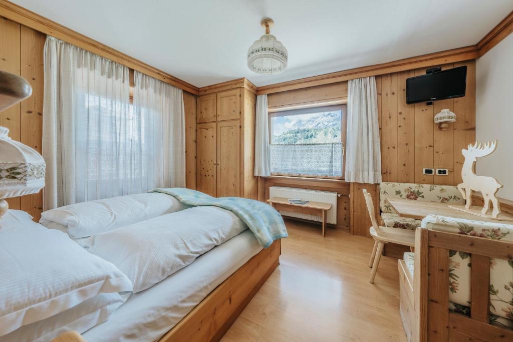 a bedroom with two beds and a table and a desk at Locanda Montana in San Vito di Cadore