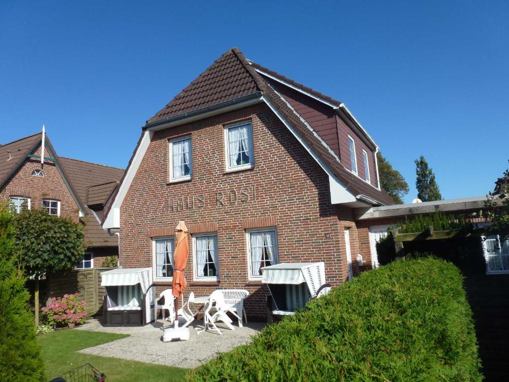 une maison en briques avec deux chaises et un parasol dans l'établissement Haus Rosi, à Wyk auf Föhr