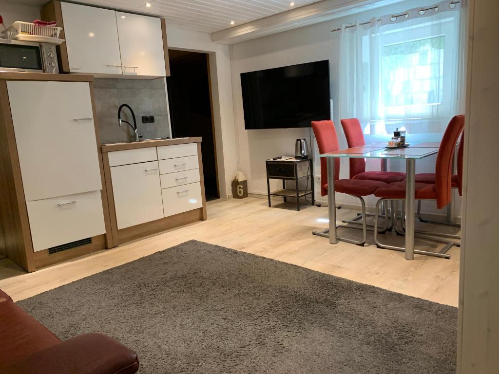 a kitchen with a table and red chairs in a room at 2-Zimmer-Whg im Souterrain mit neuer Sauna in Großenseebach