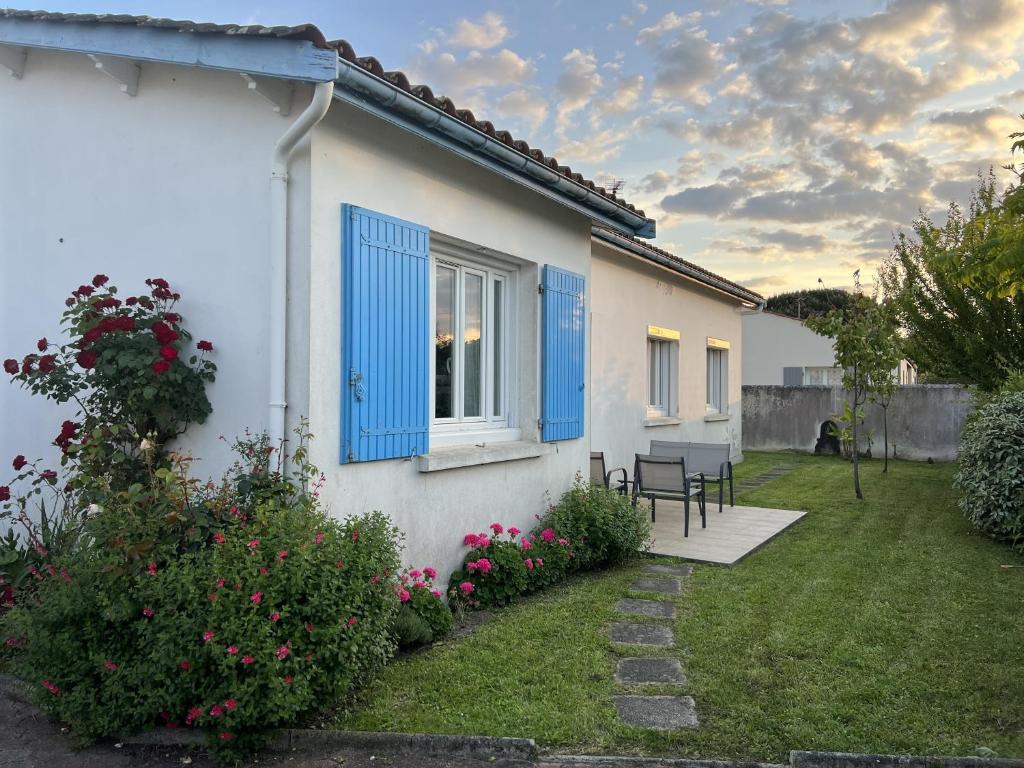a white house with blue shutters and a yard at Maison ensoleillée et reposante in Le Château-dʼOléron