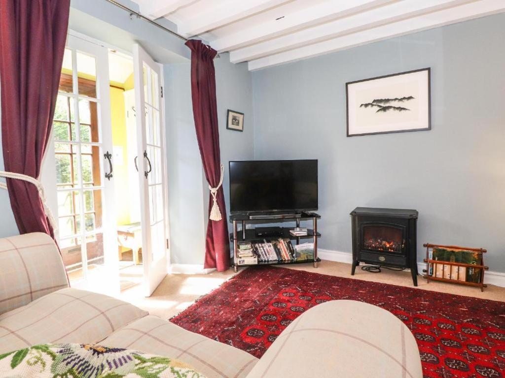 a living room with a couch and a television and a fireplace at Clover Cottage - Delightful 1-bed cottage in the heart of Ambleside in Ambleside