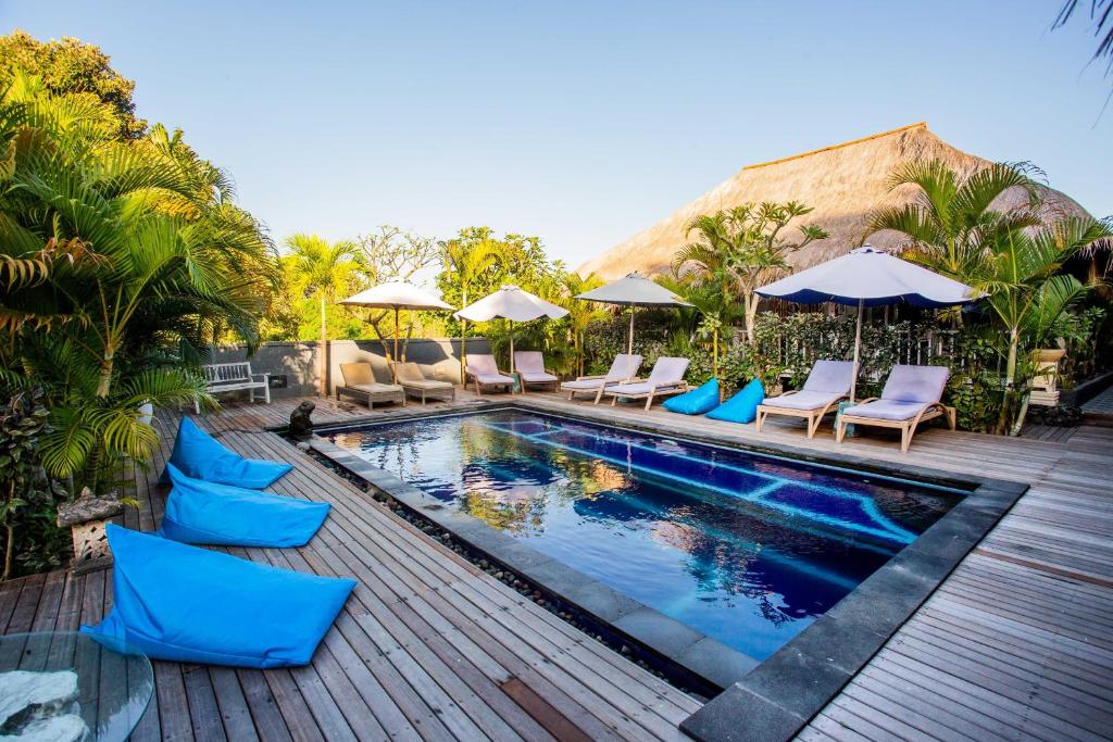 a swimming pool with blue chairs and umbrellas at Naturale Villas in Nusa Lembongan