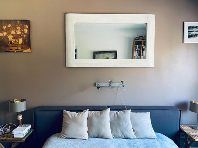 a bedroom with a blue bed with a mirror above it at Roja apartment Baltic in Roja
