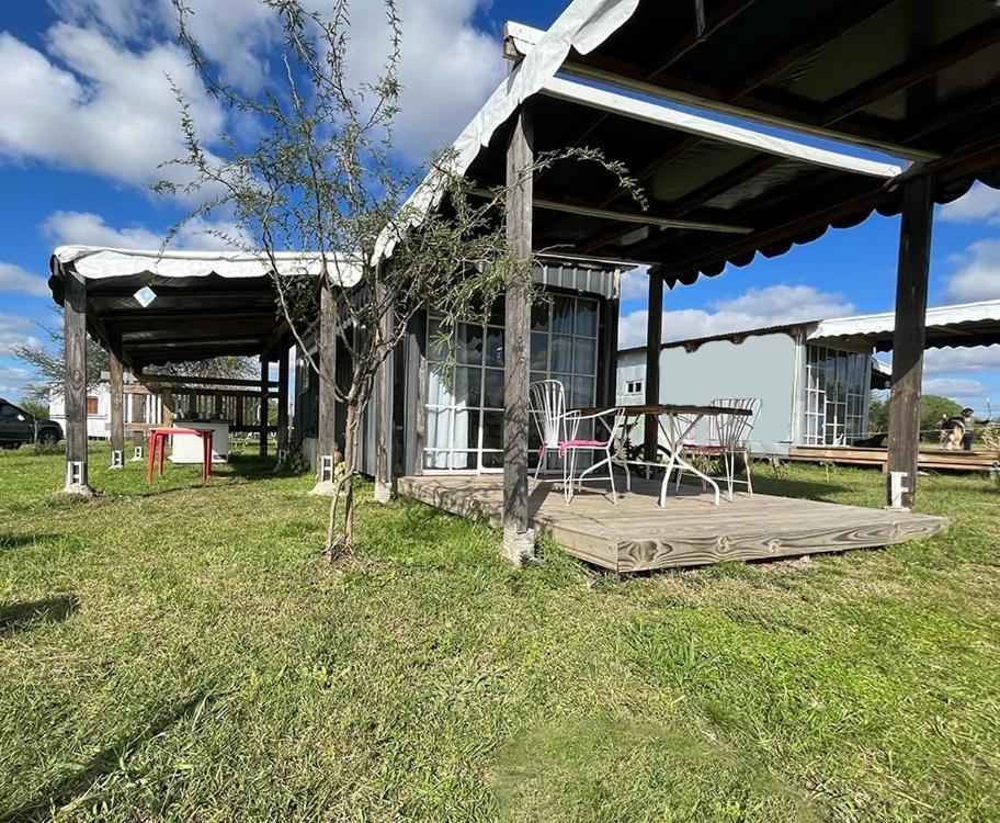 un porche de una casa con una mesa y un banco en Uy - ROMÁNTICA Cabaña en entorno Natural único, en Mercedes