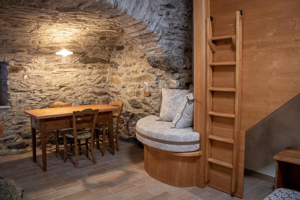 a dining room with a table and a bed in a stone wall at Busc De Crodol in Comune Rivamonte Agordino