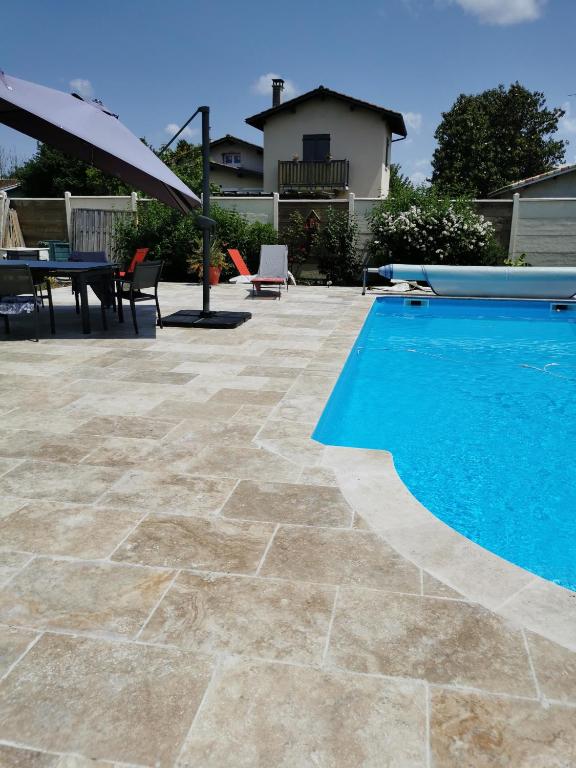 une terrasse avec une piscine et une table dans l'établissement Appartement 5 personnes avec piscine 60m2, à Le Barp