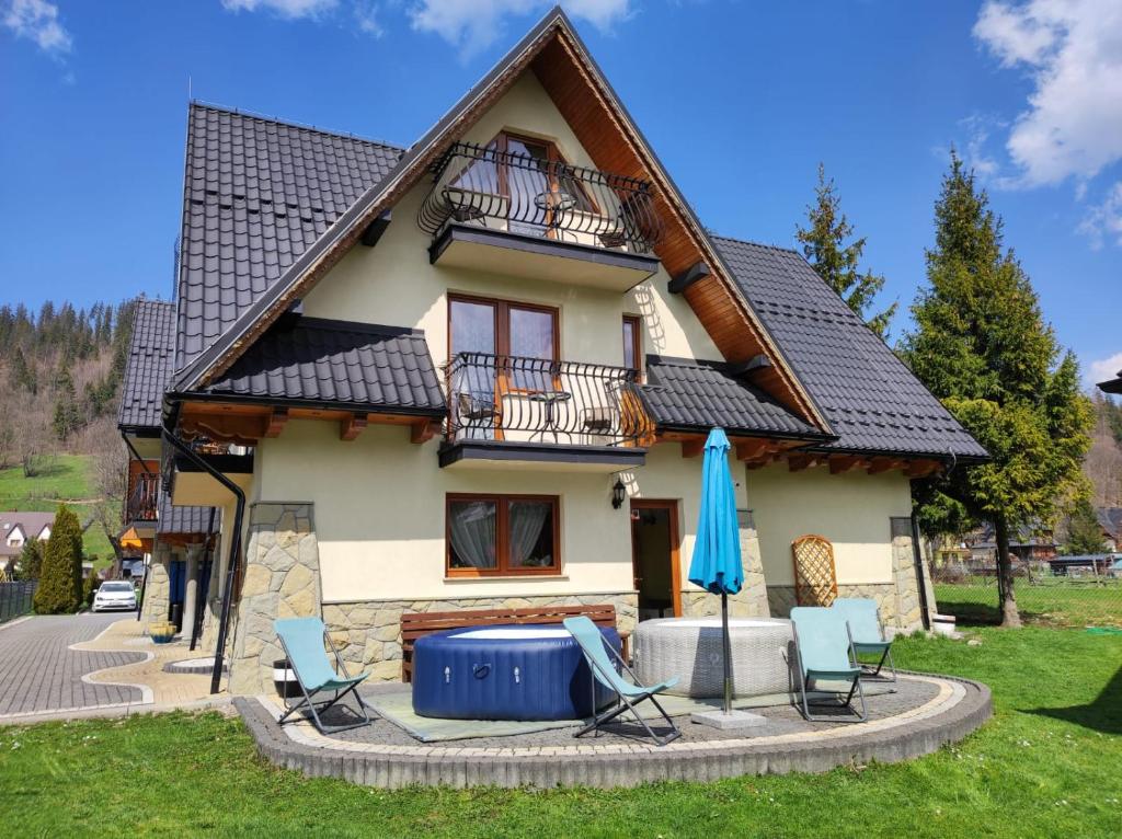 een huis met stoelen en een blauwe paraplu bij Willa Ewa in Poronin