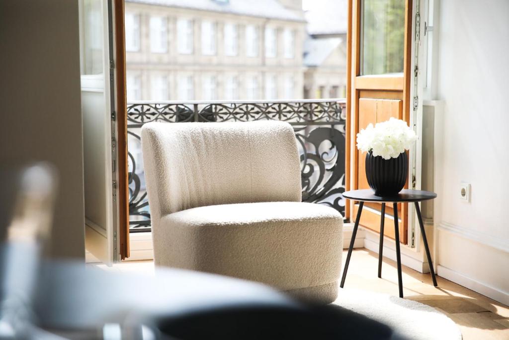 a chair sitting on a balcony with a vase of flowers at Palais Passy~Design Suite mit Ausblick im Zentrum in Wiesbaden