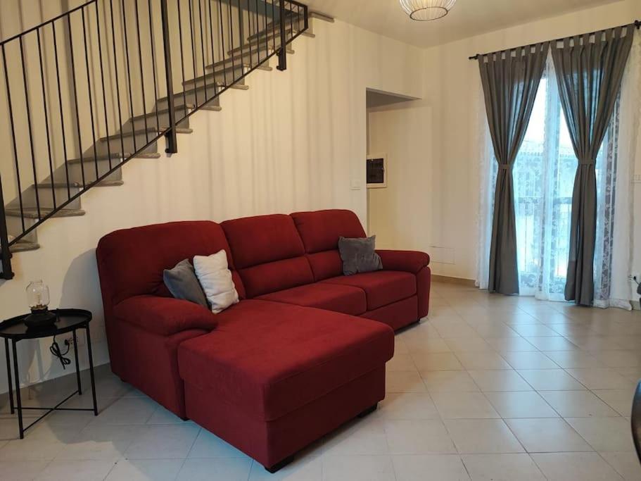 a red couch in a living room with a staircase at Il Bumbunin in Moncucco Torinese