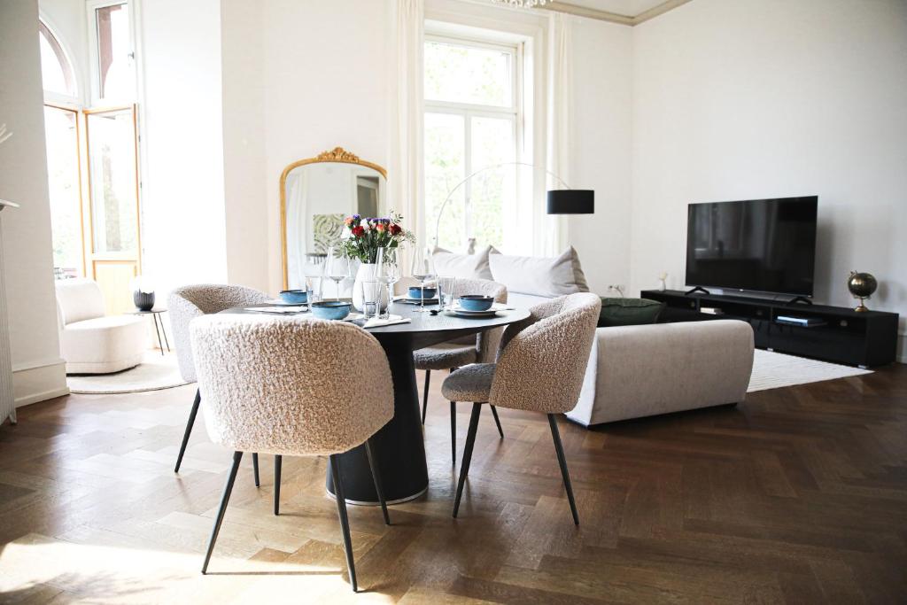 ein Wohnzimmer mit einem Tisch, Stühlen und einem Sofa in der Unterkunft Palais Passy~Design Suite mit Ausblick im Zentrum in Wiesbaden