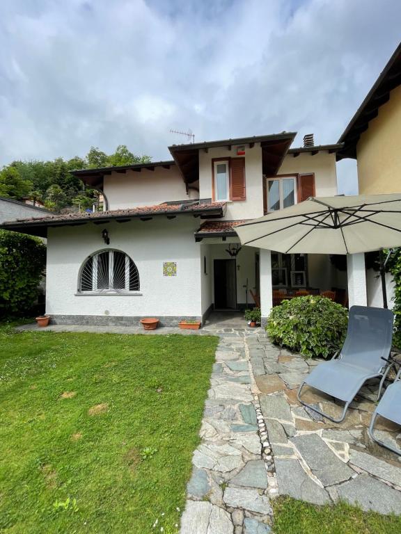 a house with an umbrella and chairs in the yard at Villa Mia Lugano Lake in Brusimpiano