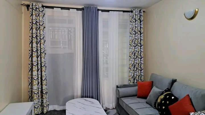a living room with a couch and a window at Lux Suites Lumumba Drive Apartments in Nairobi