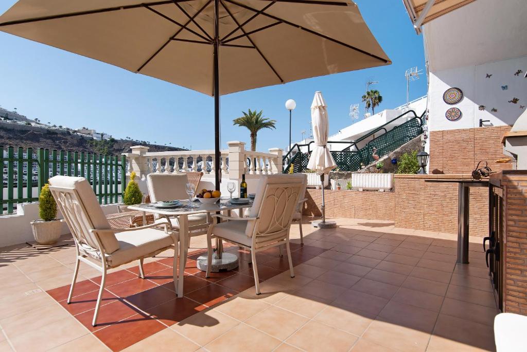 a patio with a table and chairs and an umbrella at Jolly suite puertorico Beach in Mogán