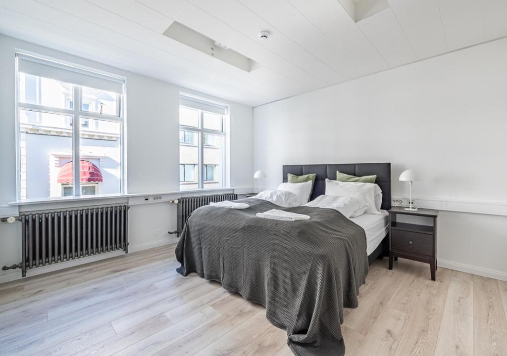 a white bedroom with a bed and two windows at Ingolfsstræti Apartments by Heimaleiga in Reykjavík