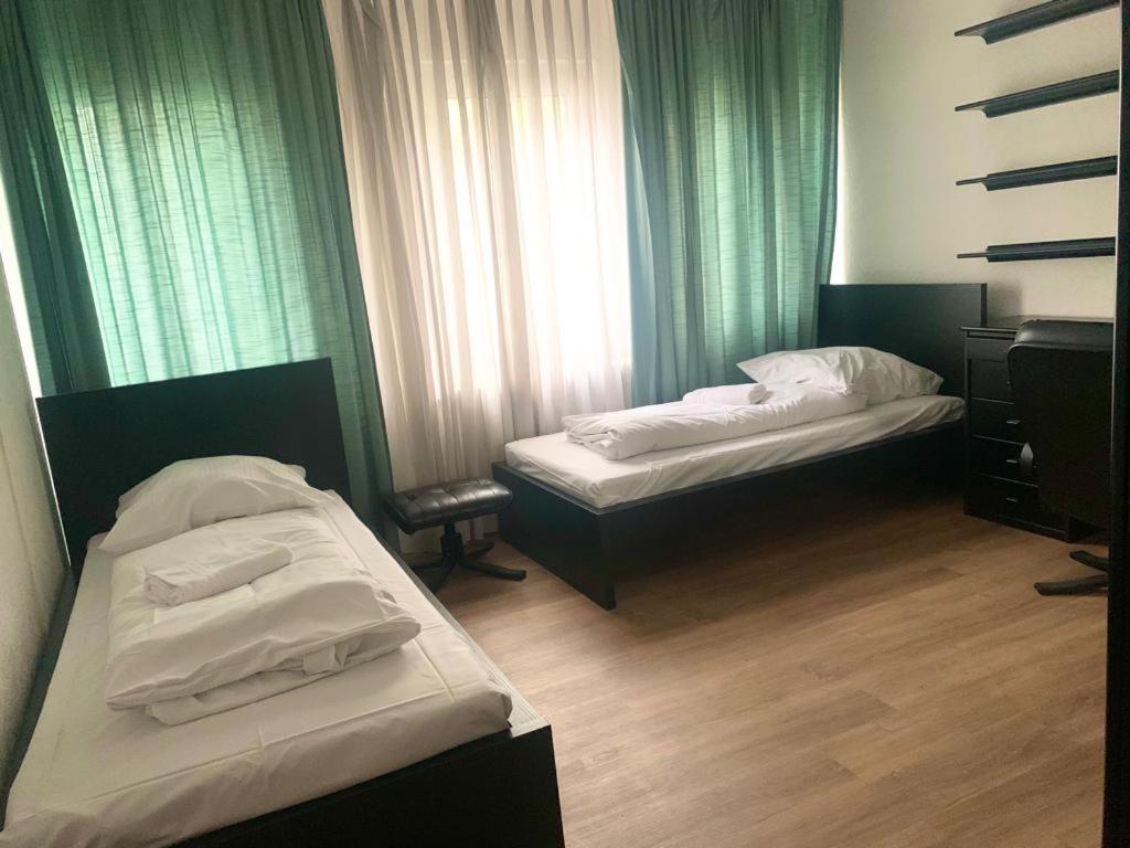 two beds in a room with green curtains at Schwalbacher Residenz in Frankfurt/Main