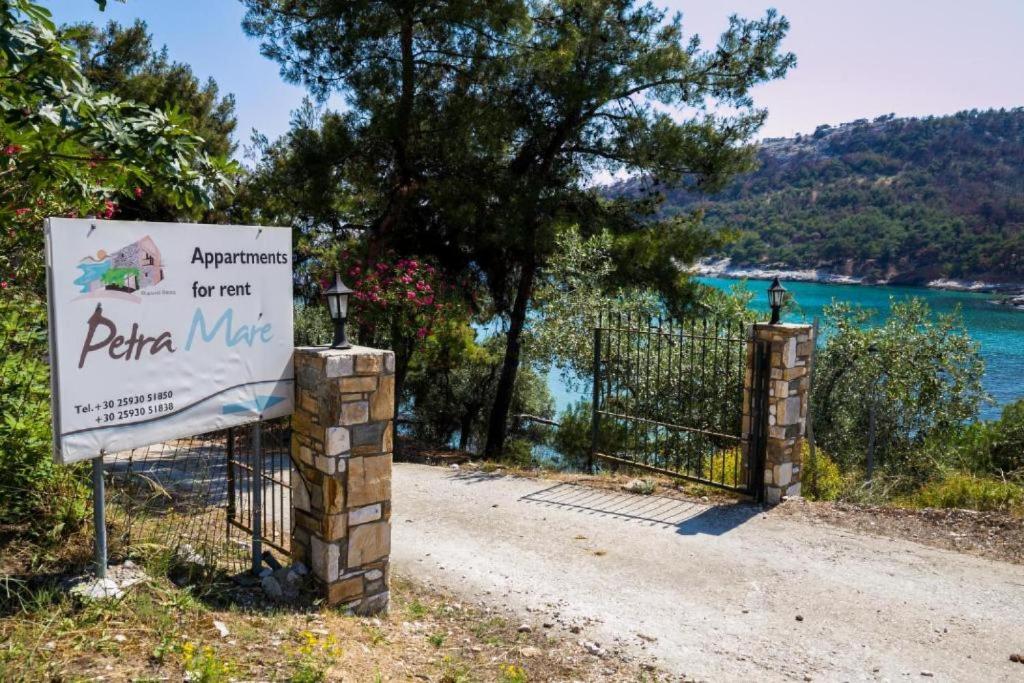 a sign in front of a gate next to the water at Petra Mare Apartments in Alyki