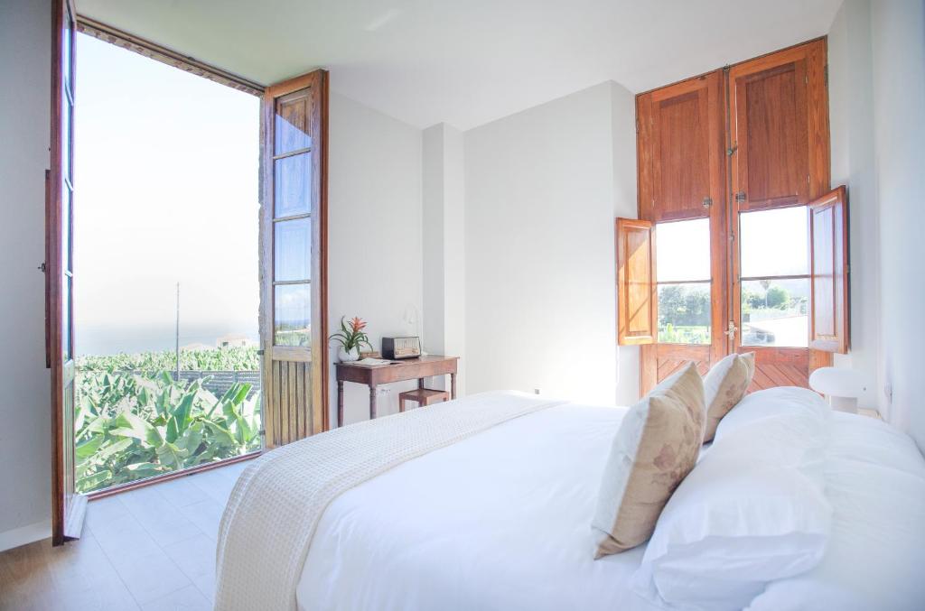 sypialnia z białym łóżkiem i dużym oknem w obiekcie Hacienda Los Orovales w Puerto de la Cruz