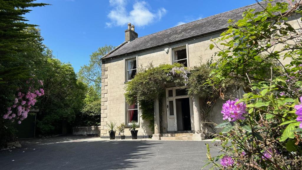 a white brick house with flowers in front of it at Annsborough House Castlewellan in Castlewellan