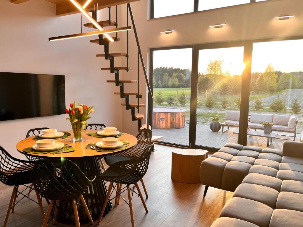 a dining room and living room with a table and chairs at Domki Grabina 