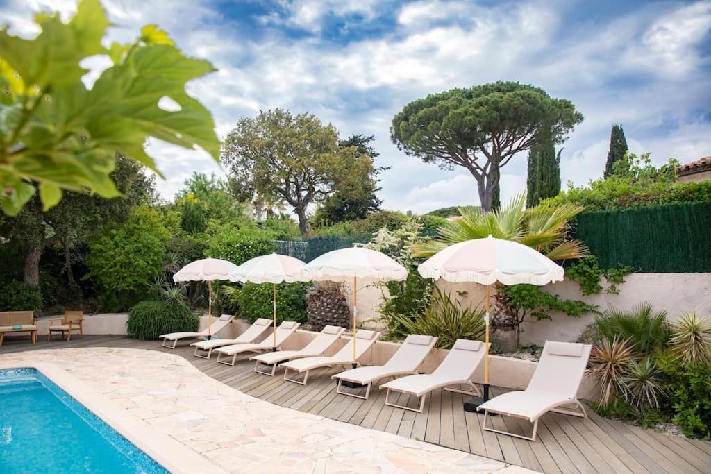 une piscine avec des chaises et des parasols à côté d'une piscine dans l'établissement Villa Pastel, à Gassin