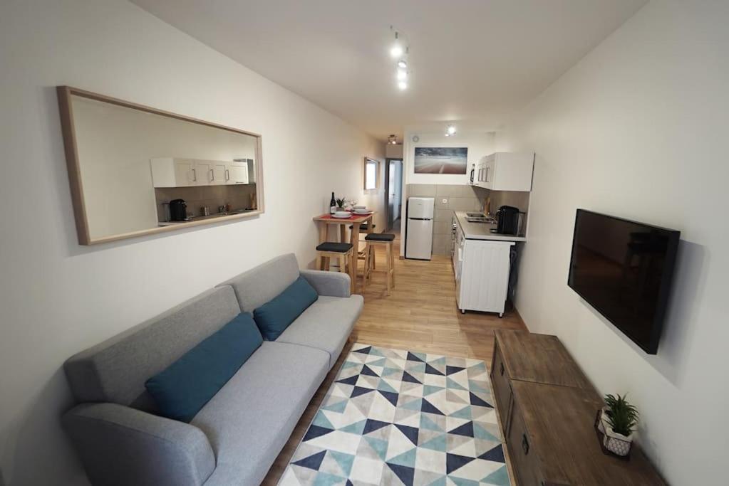 un salon avec un canapé et une cuisine dans l'établissement Le calme d'un joli patio en centre-ville, à Sète