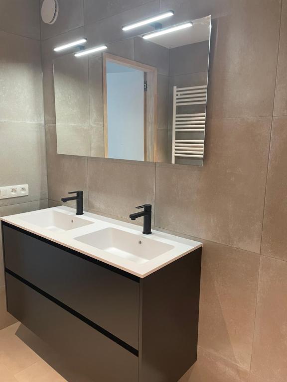 een badkamer met een witte wastafel en een spiegel bij C-dream in Blankenberge