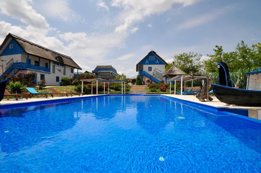 una gran piscina azul frente a una casa en Nena Art Resort, en Dunavăţu de Jos