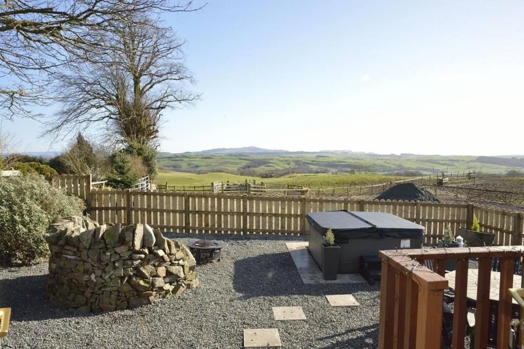 a barbecue in a yard with a wooden fence at Lochhill Stable Lodge in Castle Douglas