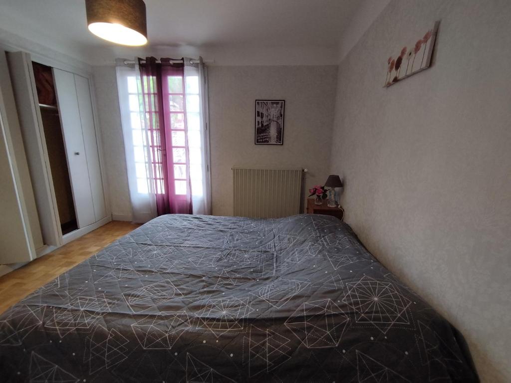 Un dormitorio con una cama con una manta. en La Maison de Raph, en Villeneuve dʼOlmes
