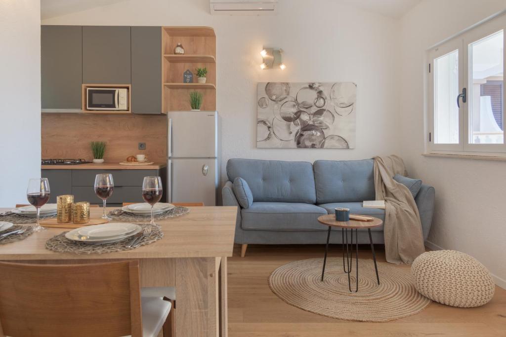 a kitchen and living room with a blue couch and a table at Cozy Apartment - 100m from the beach Punta in Pakoštane