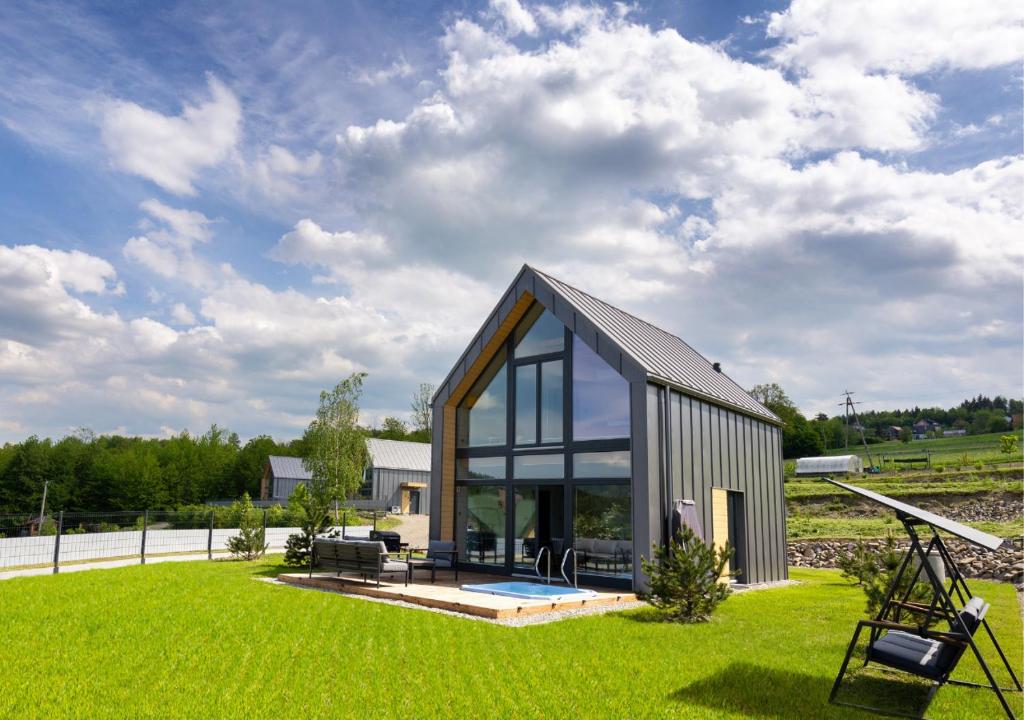 una pequeña casa con ventanas de cristal en el césped en Sośnie Górne Resort & Spa, en Grybów