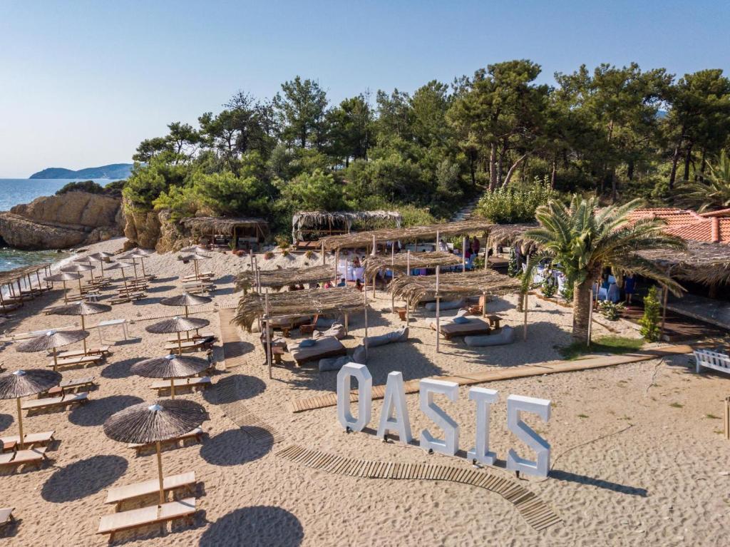 een strand met stoelen en parasols en een bord dat leest bij Oasis Deluxe Studios in Pefkari