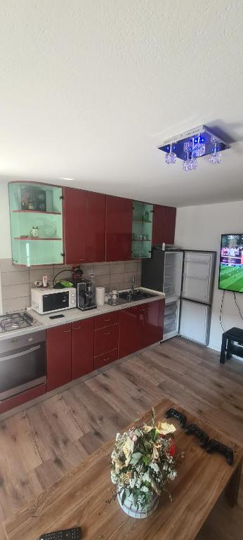 a kitchen with red cabinets and a wooden table at MM Apartman in Popovec Šašinovečki