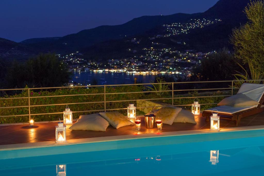 a table with candles and lights next to a swimming pool at The Bay House in Vathi, Ithaka