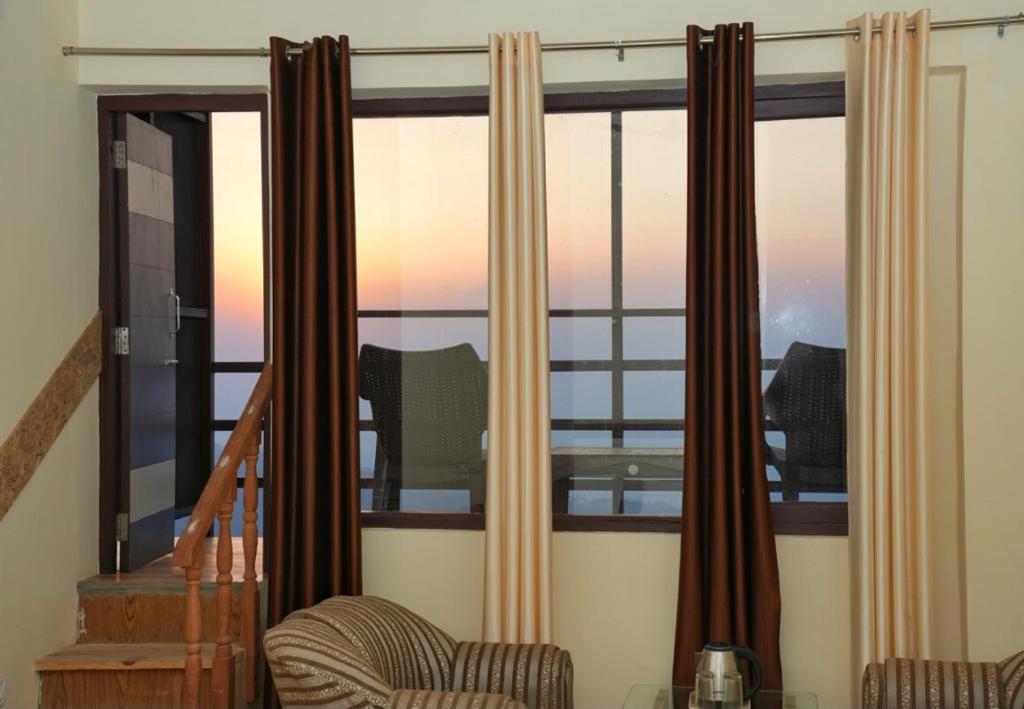 Habitación con ventana con cortinas y silla en The Hill Paradise, en Almora