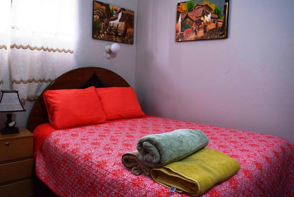a bedroom with a bed with red and yellow pillows at Carlos Guest House 1 Cusco in Cusco
