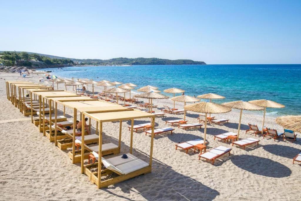 a row of umbrellas and chairs on a beach at Sotiris Studios in Pefkari
