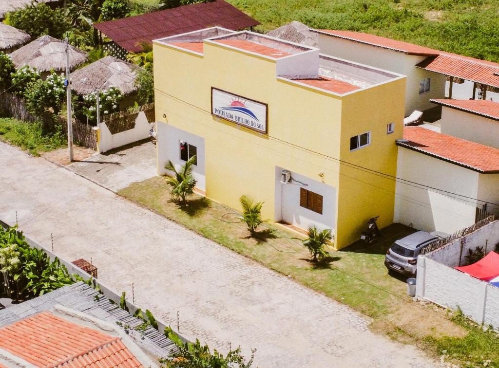 an overhead view of a yellow house with palm trees at Pousada Brilho do Sol in São Miguel do Gostoso
