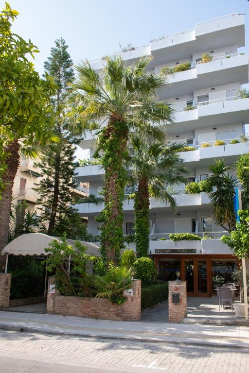 a building with palm trees in front of it at Stefanakis Hotel & Apartments in Varkiza