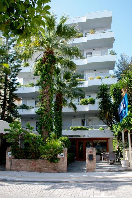 a white building with palm trees in front of it at Stefanakis Hotel & Apartments in Varkiza